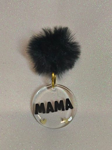 Llavero con pompon negro y la palabra "MAMA" en letras grandes y negras.